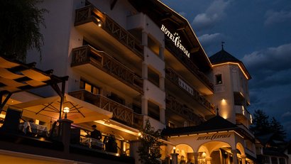 Beleuchtetes Hotelgebäude mit Balkonen und Außenbereich bei Abenddämmerung