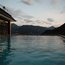 Infinity-Pool mit Bergblick bei Sonnenuntergang und Person im Wasser