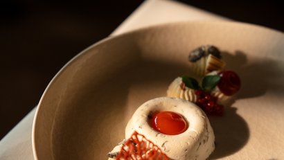 Kunstvoll angerichtetes Dessert mit rotem Gelee und Dekoration auf Teller